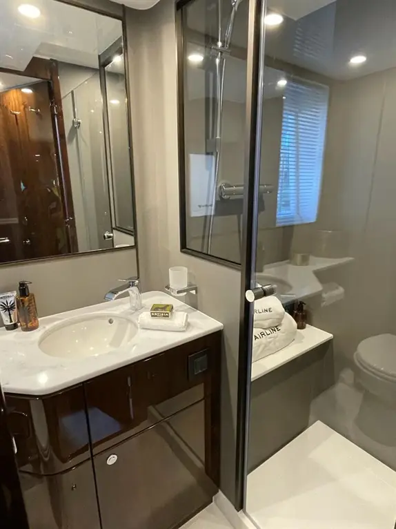 Modern bathroom featuring a shower, sink with toiletries, and neatly stacked towels labelled "AIRLINE" on a shelf.